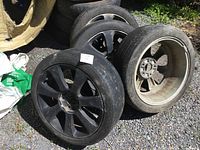 Four 17-inch black aluminum wheels with heavily worn tires mounted, showing wear, dirt, and used condition.