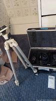 Photo showing the tripod extended and the open camera case with the Konica camera inside.