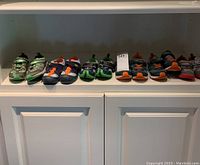 Seven pairs of boys' sneakers arranged on a shelf showing different styles and colors with normal wear.