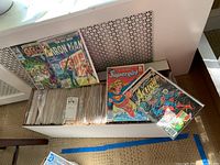 Box of comics in white box, four comics on top: Groo the Wanderer, The All-New Iron Man, Supergirl, Superman Action Comics