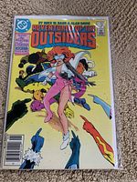 Front cover of Adventures of the Outsiders comic book with a female superhero in pink and white costume on a yellow background.