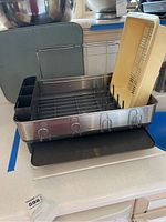 Photo showing the assembled stainless steel dish drying rack with black utensil holder on the left and yellow drain tray below.
