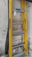 Side view of yellow ladder showing multiple metal steps and visible weathering.