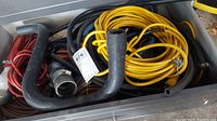 Photo showing yellow extension cord, black hoses, red cables, and metal hose connector inside a drawer.