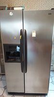 Full front view of stainless steel Kenmore Coldspot side-by-side refrigerator and freezer unit with water and ice dispenser on freezer door.
