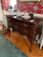 Photo of cherry wood server from side angle showing damage and drawer fronts with brass hardware.