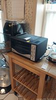 Power Air Fryer Oven with recipe book and accessories on the top of a kitchen cart, next to a Cuisinart toaster oven and electric kettle.