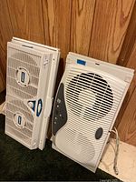 Front view of Lasko window fan showing dual fan blades, dials, and logo, next to Patton expandable fan with control panel on the side.