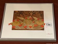 Full view of the framed artwork showing three frogs made from leaves and grasses, signed, with orange flower eyes and feet on a brown leaf-patterned background.