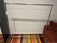 Full view of the metal clothing rack showing the rectangular frame with a horizontal bar for hanging clothes and caster wheels on the base.
