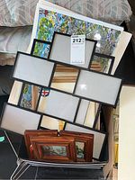 Large multi square photo frame resting on a chair with several framed and unframed prints stacked underneath. Laminated map partially visible beneath.