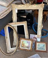 Photo showing three large ornate carved frames and three framed art pieces, two prints and one original painting.