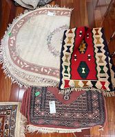 Top view of three rugs stacked on hardwood floor showing their colors and patterns clearly.