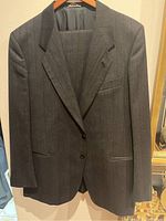 Front view of dark pinstripe Harry Rosen suit jacket, made in Italy, hanging on a wooden hanger.