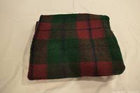 Folded view of the fleece throw showing the green and red plaid pattern and fabric texture.