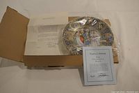 Photo showing the original box, certificate of authenticity, and collector plate with part of the design visible.