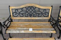 Bench with decorative cast iron backrest and wood slat seating showing weathering and need for refinishing.