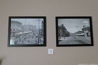 Two framed black and white photographs displayed on a wall side by side showing historical street scenes of Denver and Boulder Colorado.