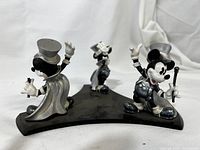 Three resin Mickey Mouse magician figurines mounted on a black plastic stand, showing general condition and mounting style.