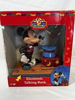 Front view of Mickey Mouse electronic talking bank in original box with red and yellow packaging showing wear.