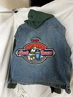 Full rear view of denim jean and green sweatshirt hooded jacket with large embroidered Mickey Mouse 'Gas & Grease' patch on back.
