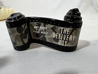 Front view of black ceramic film roll sculpture with Disney text and Mickey Mouse silhouettes