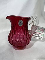Front side view of the Fenton cranberry glass pitcher with original label
