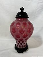 Front view of complete covered jar with black lid and base.