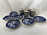 Full view of mixed collection including six blue and white oriental plates, two lidded pitchers, and a glass creamer