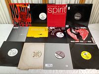 12 LP albums laid out on table showing front album covers and white label records on some sleeves. Various colors and designs visible.