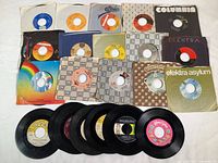 24 vintage 45 RPM records grouped with some in sleeves showing various labels such as Epic, Columbia, Elektra, Asylum, ATCO, RCA, EMI