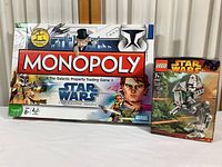 Photo of Star Wars Monopoly The Clone Wars Edition game box and sealed Lego Star Wars Clone Scout Walker kit box on white surface