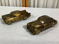 Two vintage metal car coin banks, 1957 Chevy and 1946 Sedan, shown side by side