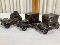 Three vintage metal coin bank cars from Banthrico, each modeled after early 1900s automobiles, showing a group view from front and side.