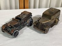 Two vintage metal coin banks - a fire truck and a delivery van, showing overall condition and size comparison.
