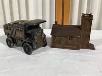 Mack Truck and Little Brown Church coin banks side by side on table, showing overall size and shape.