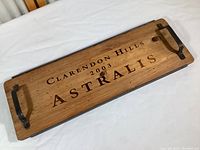 Top down view of wooden serving tray with wine crate style branding and forged metal handles.