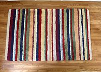Top view of the striped wool carpet showing multicolor vertical stripes and texture on hardwood floor.