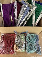Box containing multiple braided Mokuba ribbons in various colors, some on cards with Japanese writing.