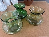 Three colored glass vases including two green and one amber, all with ruffled edges and round bases.