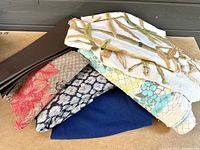 Collection of mixed fabric pieces showing various colors and patterns including embroidered cream fabric, floral, solid blue, red floral and geometric patterns.