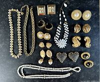Full overview of the costume jewelry lot showing two necklaces and multiple pairs of clip-on earrings arranged neatly.