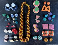 Full display of the lot with earrings and necklace arranged on black surface.