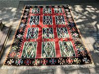 Full view of rug laid flat outdoors showing overall geometric pattern and condition