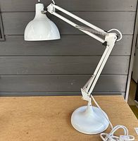 Side view of the white adjustable desk lamp showing arm, base, and lamp head.