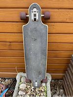 Top view of skateboard showing black grip tape surface and wear marks