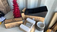Lot of household items including shower caddy in box, black organizer, black vase, and a ceramic pot