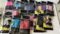Overview of 20 HQ durags in sealed black and clear packages, showing multiple colors and styles piled on a flat surface.