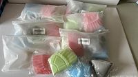 Lot of 6 packs of silicone air fryer accessories still in plastic packaging, showing multiple colors and accessory shapes.