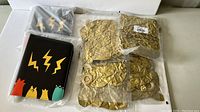 Two Pokémon card holder binders and eight sealed packs of gold balloons with a metallic finish.